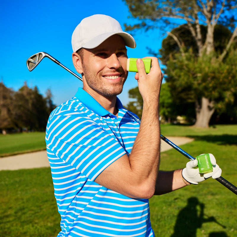 Man applying Outbound sun stick holding a golf club and a golf ball on a golf course